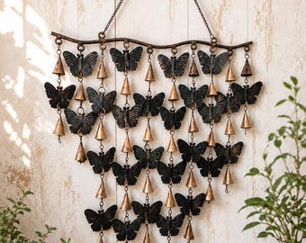 May include: A wall-hanging wind chime featuring a horizontal branch-like bar suspended by a chain. Multiple dark, textured butterfly silhouettes are arranged in a cascading pattern, interspersed with small, metallic, cone-shaped bells.