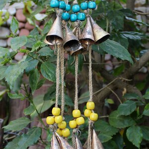 Puede incluir: Un conjunto de carillones con múltiples campanas y cuentas de colores. Las campanas son plateadas y las cuentas son naranja, azul, amarillo y rojo.