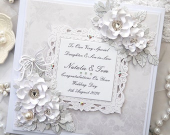 May include: White wedding card with silver glitter and a white paper flower embellishment. The card reads "To Our Very Special Daughter & Son-in-Law Natalie & Tom Congratulations On Your Wedding Day 8th August 2024".