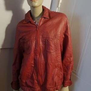 Peut inclure: Une veste en cuir rouge avec une fermeture éclair et deux poches à rabat. La veste a un col et des manches longues.