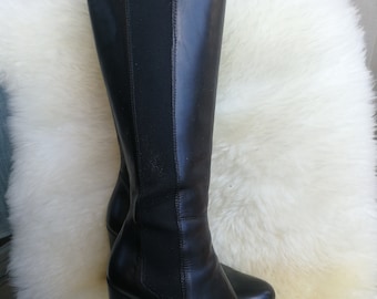 May include: Black leather knee-high boots with a block heel. The boots have a stretchy panel on the back of the shaft.