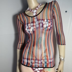 May include: A multi-colored striped top with three-quarter sleeves and a black trim. The top is displayed on a mannequin. The stripes include shades of orange, blue, and purple. The mannequin also has a matching bottom.