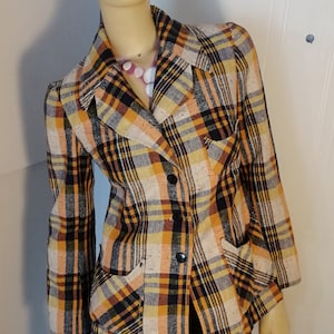 Peut inclure: Un blazer à carreaux avec un motif brun, orange et noir. Le blazer a une fermeture à double boutonnage et deux poches à rabat.