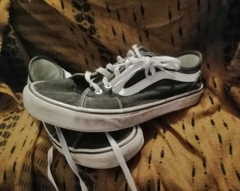 May include: Pair of black and white canvas sneakers with white laces. The shoes have a white rubber sole and a white stripe on the side. The sneakers are sitting on top of each other.