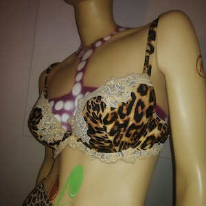 Peut inclure: Un soutien-gorge à imprimé léopard avec une bordure en dentelle. Le soutien-gorge est sur un mannequin avec un motif peint sur la poitrine.