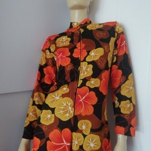 Peut inclure: Une robe à manches longues avec un fond noir et un imprimé floral dans les tons orange, jaune et marron.