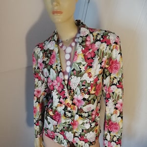 May include: A floral print blazer with a black background. The blazer has a button closure and long sleeves. The flowers are pink, white, and yellow.