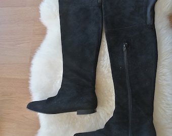 May include: A pair of black over-the-knee boots with a suede finish. The boots have a pointed toe and a low heel.