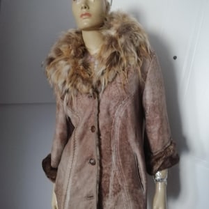 Peut inclure: Un manteau en daim marron avec un col et des poignets en fourrure. Le manteau a une fermeture boutonnée sur le devant et une coupe ajustée. Le col en fourrure est un mélange de tons marron et beige. Le manteau est présenté sur un mannequin.