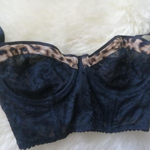 May include: Black lace bra with leopard print trim. The bra has a bustier style and adjustable straps.