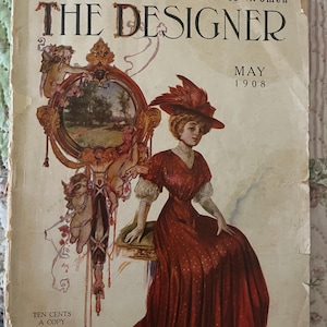 May include: Vintage magazine cover for "The Designer" from May 1908. The cover features a woman in a red dress and hat, seated near a decorative mirror. The magazine's title and pricing are also visible.