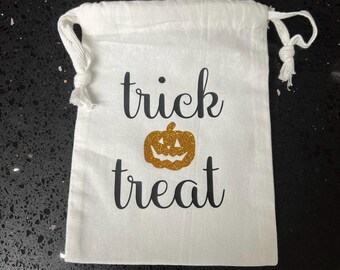 May include: White cotton trick or treat bag with a gold glitter pumpkin and black text.