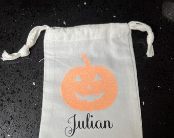 May include: White Halloween treat bag with a pink glitter pumpkin and the name Julian printed in black.