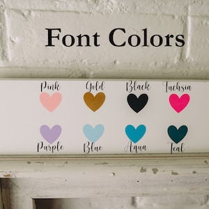 Op de afbeelding: Een wit bord met de tekst "Font Colors" bovenaan. Het bord toont acht hartvormen in verschillende kleuren: roze, goud, zwart, fuchsia, paars, blauw, aqua en teal. Elke hartvorm heeft de kleurnaam eronder.
