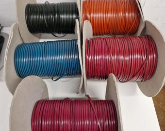 May include: Five spools of round leather cord in black, orange, blue, red, and dark pink. Each spool is made of cardboard and holds a continuous length of cord wrapped around the center. The cords are smooth and uniform in thickness.