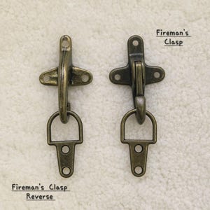 May include: Two antique brass-colored fireman's clasps. One is open, the other closed. The text "Fireman's Clasp" is above the closed clasp. Below the open clasp is the text "Fireman's Clasp Reverse".