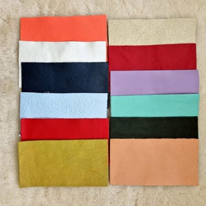 May include: A selection of rectangular leather swatches in a range of colours, such as orange, white, navy blue, light blue, red, gold, beige, red, lavender, teal, black, and peach. The swatches are arranged in two columns, displaying the different textures and shades.