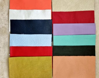 May include: A collection of rectangular leather swatches in various colors, including orange, white, navy blue, light blue, red, gold, beige, red, lavender, teal, black, and peach. The swatches are arranged in two columns, showcasing the different textures and hues.
