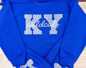 May include: Royal blue sweatshirt with silver glitter lettering that reads "KY Wildcats". The sweatshirt has silver glitter bows on the cuffs.