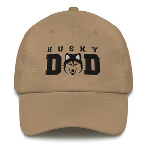May include: A khaki dad hat with black embroidery that reads "HUSKY DAD" and features a black and white husky silhouette.