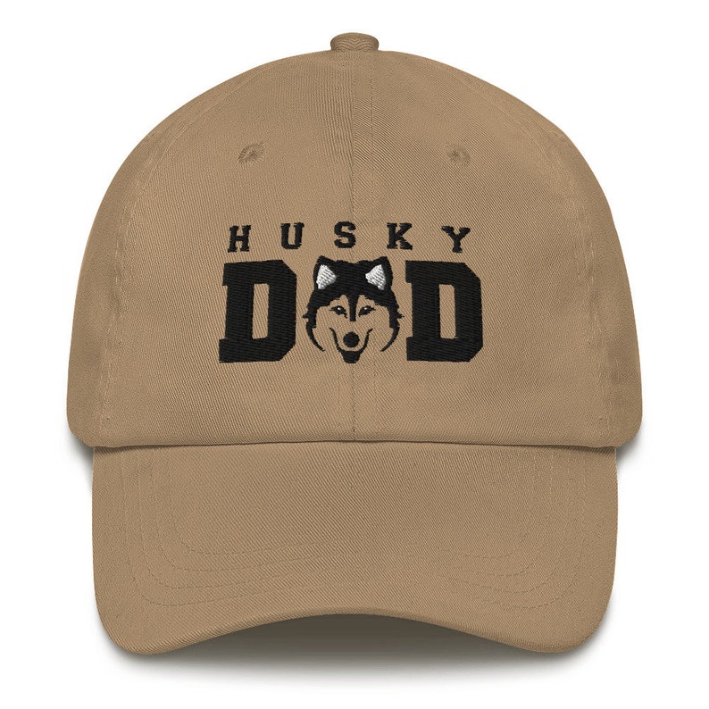May include: A khaki dad hat with black embroidery that reads "HUSKY DAD" and features a black and white husky silhouette.