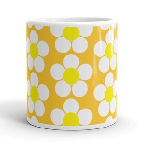 May include: A yellow mug with a white daisy pattern. The daisies have yellow centers.