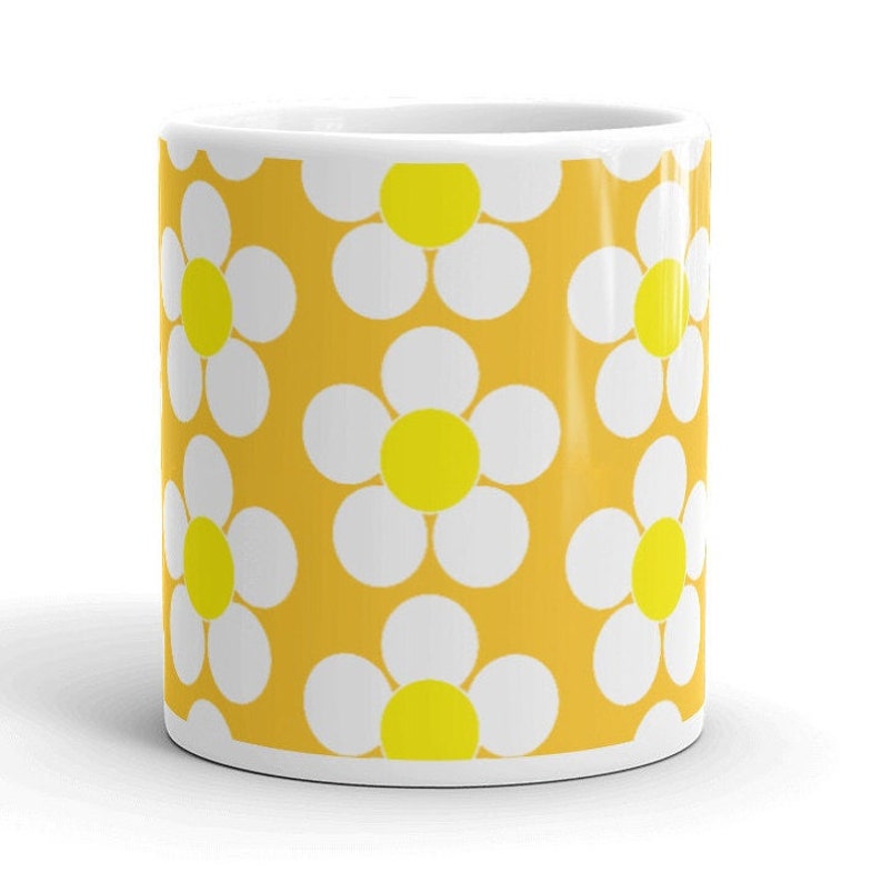 May include: A yellow mug with a white daisy pattern. The daisies have yellow centers.