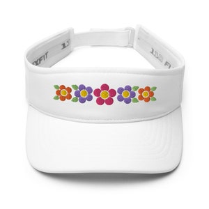 May include: White visor with a row of five embroidered flowers in orange, purple, pink, purple, and orange. The flowers have green leaves.
