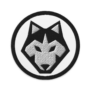 Può includere: Toppa ricamata in bianco e nero di una testa di lupo all'interno di un cerchio nero.