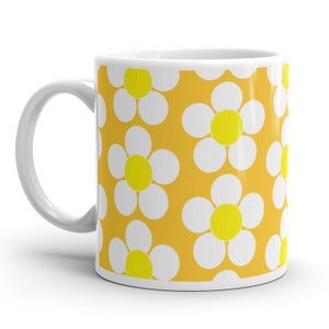 May include: White ceramic mug with a yellow background and a repeating pattern of white daisies with yellow centers.