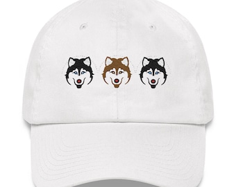 May include: White baseball cap with three embroidered husky dog faces. The dogs are black and white, brown and white, and black and white with blue eyes.
