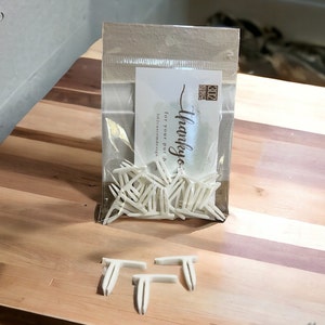 May include: A bag of white plastic T-shaped furniture connectors. The bag is labeled "thank you... for your purchase" and "312 Custom Designs". Three connectors are shown outside of the bag.