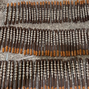 May include: A large quantity of chocolate-covered pretzel sticks decorated with white icing to resemble footballs.
