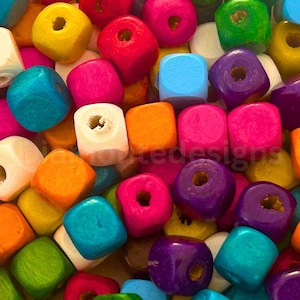Può includere: Una collezione di piccole perline di legno a forma di cubo in una varietà di colori vivaci, tra cui rosso, arancione, giallo, verde, blu, viola, rosa e bianco. Ogni perlina presenta un foro centrale per l'infilatura, con finitura opaca.