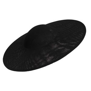 Puede incluir: Un sombrero negro para el sol con ala ancha y copa redondeada. El sombrero está hecho de un material tejido, y el ala tiene aproximadamente 40 cm de diámetro. El sombrero está diseñado para dar sombra del sol.