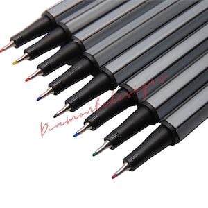 Puede incluir: Un conjunto de diez marcadores negros de punta fina con tinta de colores. Los marcadores tienen un cuerpo rayado plateado y negro y una tapa negra.