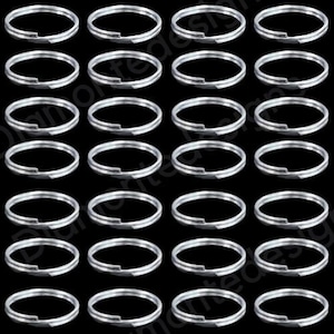 May include: A collection of silver split key rings arranged on a black backdrop. The key rings are circular with a split section for attaching keys or other objects. The rings are uniformly spaced and seem to be made of metal.