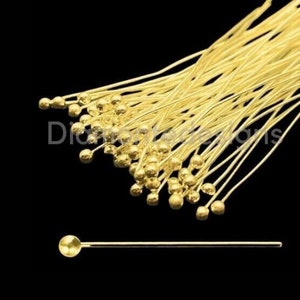 May include: A bunch of gold head pins with round heads. The pins are approximately 2.5 cm long.