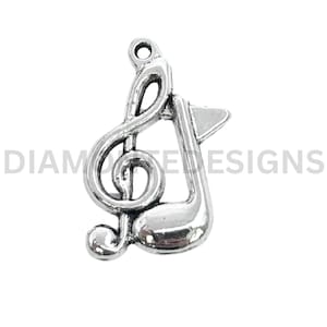 May include: A silver-colored charm featuring a treble clef and a musical note. The charm has a loop at the top for attaching to a necklace or bracelet. The word "DIAMONDE DESIGNS" is printed on the image.