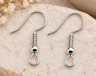 Puede incluir: Un par de ganchos para pendientes de metal plateado con un alambre curvado, un detalle de resorte en espiral, una pequeña cuenta decorativa y un bucle inferior para sujetar componentes de joyería. Estos fornituras sirven para crear pendientes.