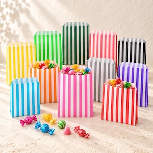 Pode incluir: Uma coleção de sacos de papel para doces com riscas verticais em várias cores, incluindo amarelo, verde lima, verde escuro, rosa, preto, azul, laranja, roxo e vermelho, com vários rebuçados embrulhados espalhados à frente.