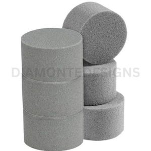 May include: A stack of three cylindrical grey foam blocks positioned next to two additional cylindrical grey foam blocks. The surface of each foam piece has a porous, textured appearance. The text DIAMONTEDESIGNS is visible in the background.