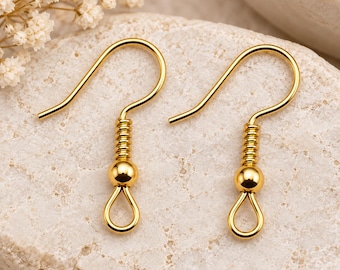 May include: A pair of gold-toned metal earring hooks featuring a curved wire, a coiled spring detail, a small polished bead, and a closed loop at the bottom for attaching jewelry components. These findings are designed for creating custom earrings.