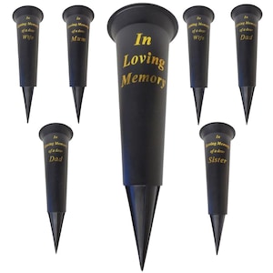 Könnte beinhalten: Schwarze Gedenk-Blumenvasen mit spitzer Basis. Die Vasen tragen goldfarbene Schriftzüge mit der Aufschrift „In Loving Memory“ und Namen wie „Wife“, „Mum“, „Dad“ und „Sister“.