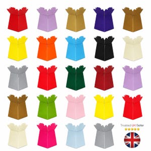 May include: A collection of twenty-five square-based cardboard flower boxes in various solid colours including red, yellow, blue, green, black, white, silver, gold, pink, and purple, each featuring a decorative scalloped top edge design.