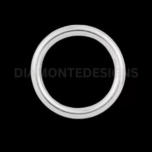 May include: A silver ring with a circular design, set against a black background. The ring is smooth and reflective, with the text "DIAMONTEDESIGNS" visible. This piece is suitable for jewelry.