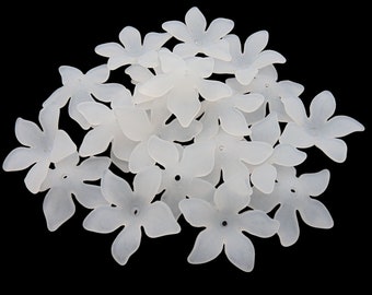 May include: A group of 15 white plastic flower embellishments with five petals each. The flowers are translucent and have a slightly frosted appearance.