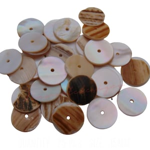 Puede incluir: Un montón de botones redondos, planos, blancos y marrones de concha con un agujero en el centro. Los botones están hechos de materiales naturales y tienen un aspecto rústico y orgánico.