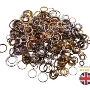 May include: A large pile of mixed metal jump rings in silver, gold, and bronze colours. The rings are various sizes and are perfect for jewellery making.