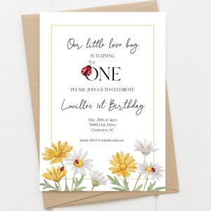 May include: A white invitation card with a gold border. The card features a ladybug illustration and the text "Our little love bug is turning ONE. Please join us to celebrate Lucille's 1st Birthday. May 20th at 4pm 5000 Oak Drive Charleston, SC Kindly RSVP to kate@email.com". The card is decorated with yellow and white daisies.